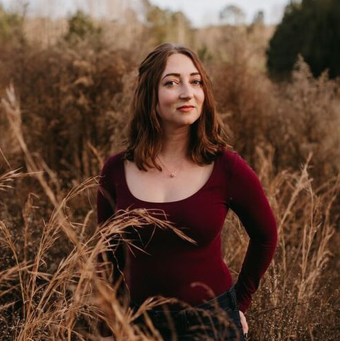 A woman, Jackie, smiling and posing in a field of some sort.