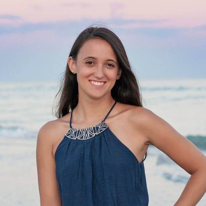 A woman, Rachel, smiling and posing at the beach.